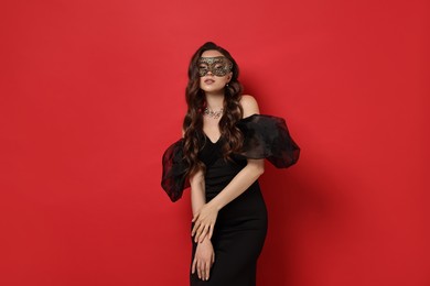 Beautiful woman wearing carnival mask on red background