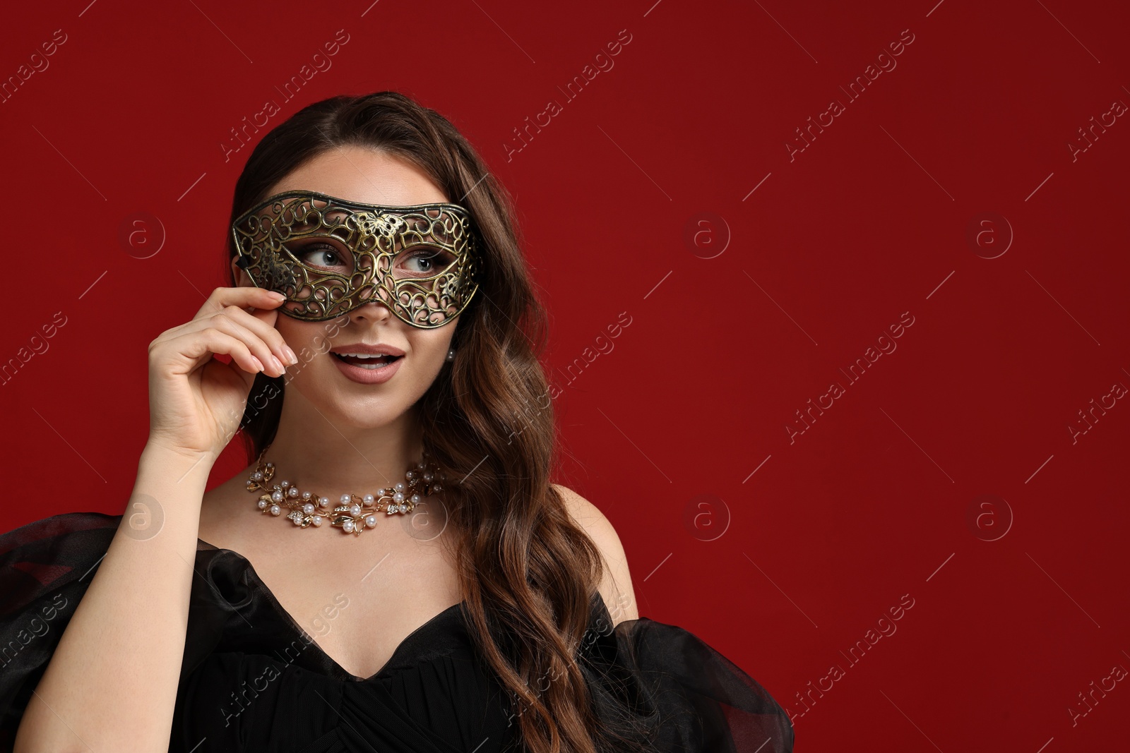 Photo of Beautiful woman wearing carnival mask on red background. Space for text