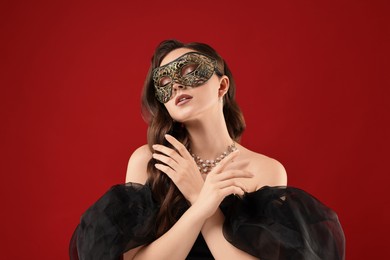 Beautiful woman wearing carnival mask on red background