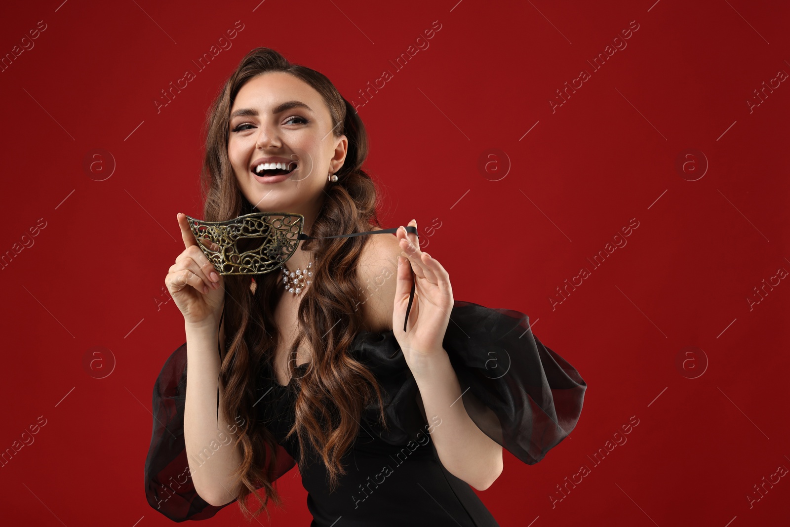 Photo of Happy woman with carnival mask on red background. Space for text