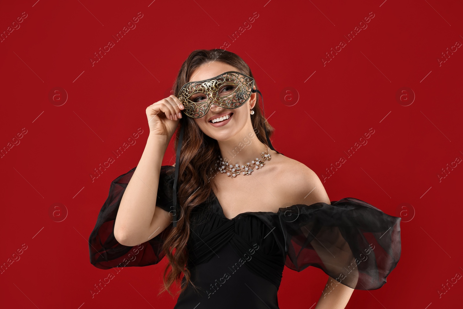 Photo of Happy woman wearing carnival mask on red background