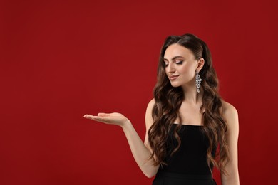 Portrait of charming woman holding something on red background. Space for text