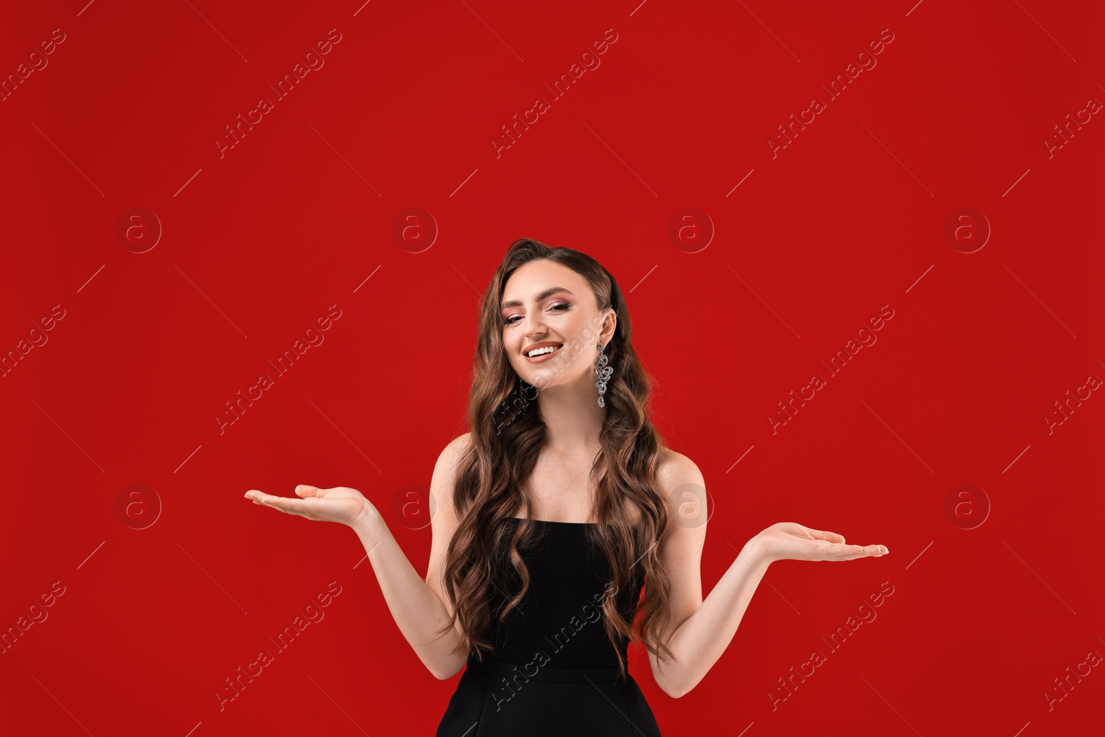 Photo of Portrait of smiling woman holding something on red background