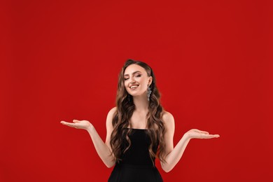 Portrait of smiling woman holding something on red background