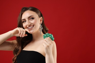 Photo of Smiling woman with poker chips on red background. Space for text