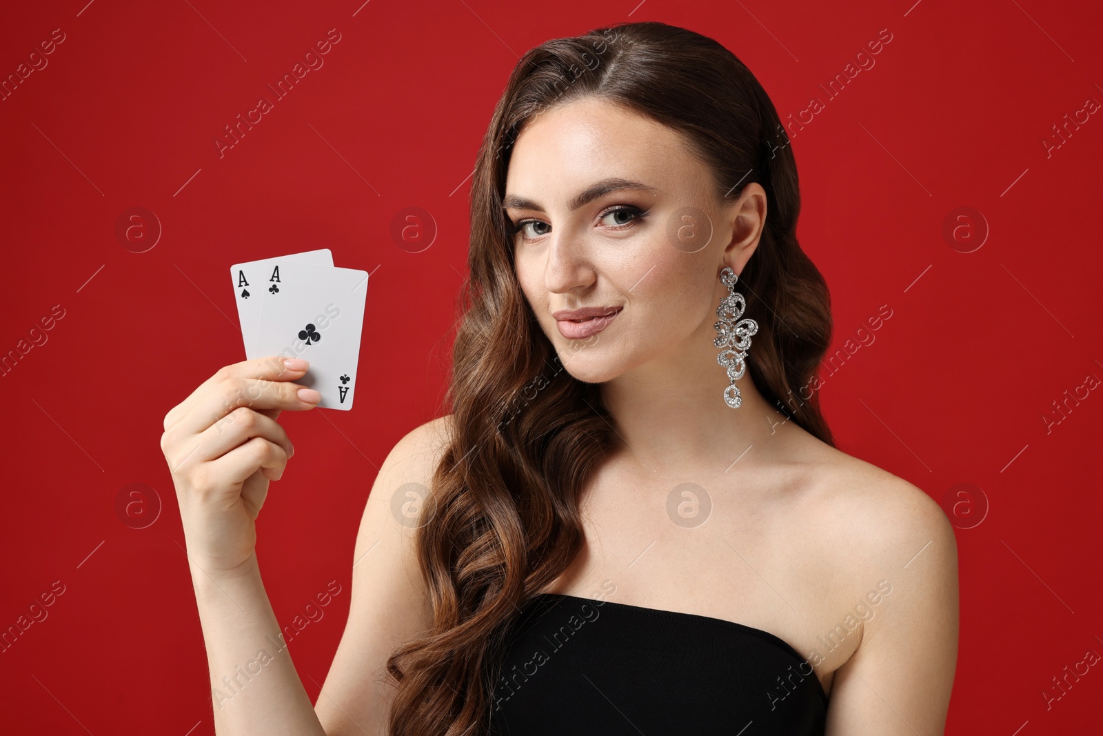 Photo of Poker game. Charming woman with playing cards on red background