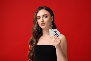 Photo of Poker game. Charming woman with playing cards on red background