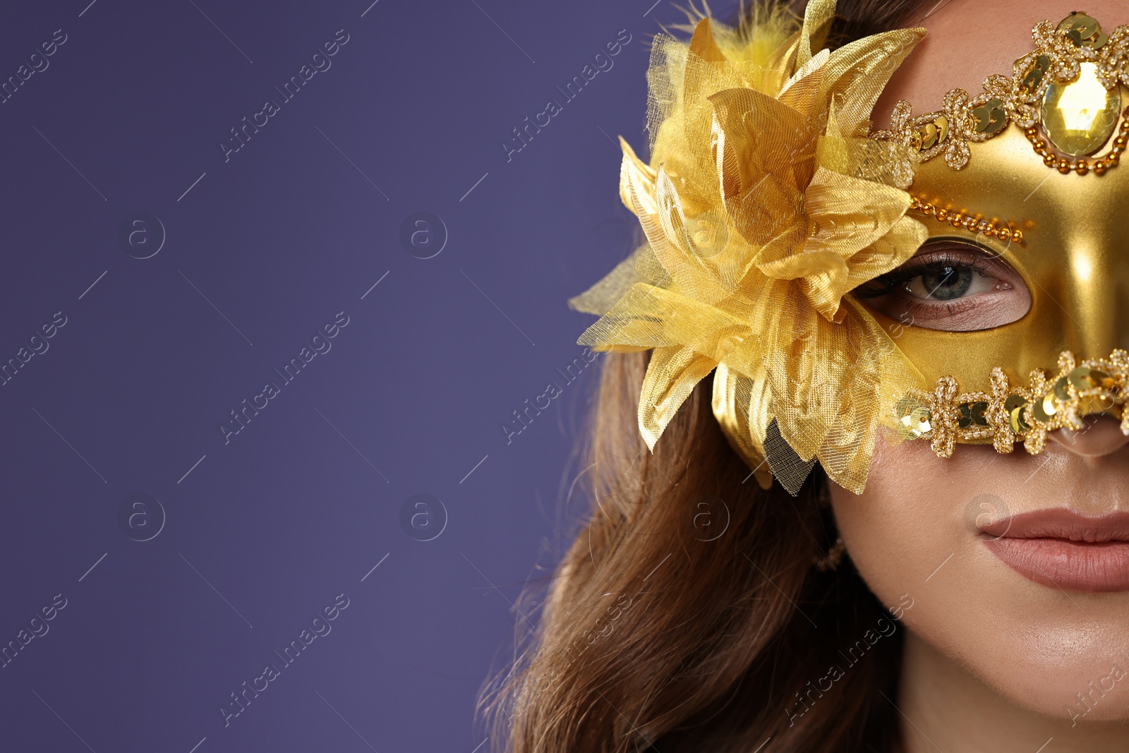 Photo of Beautiful woman wearing carnival mask on purple background, closeup. Space for text