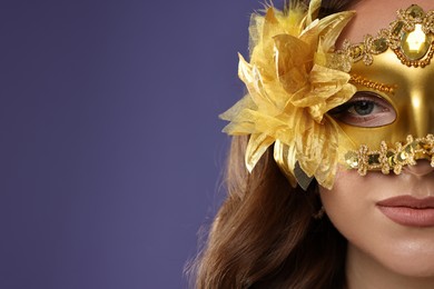 Beautiful woman wearing carnival mask on purple background, closeup. Space for text