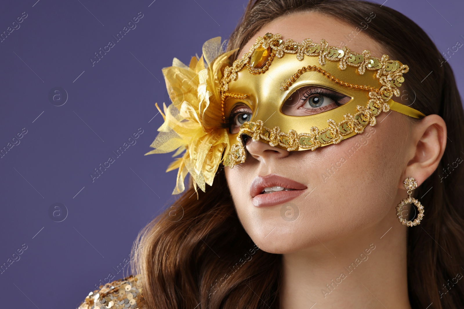 Photo of Beautiful woman wearing carnival mask on purple background, closeup. Space for text