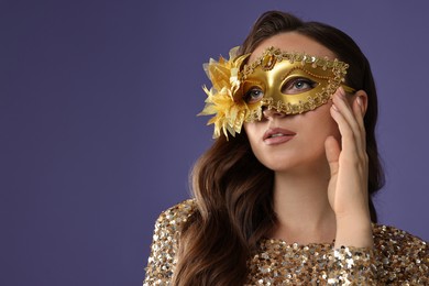 Beautiful woman wearing carnival mask on purple background, closeup. Space for text