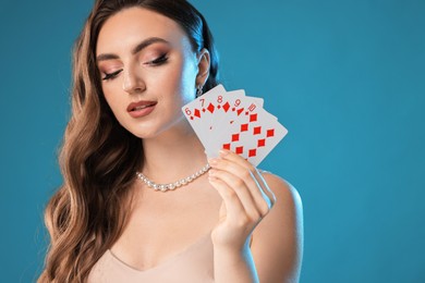 Photo of Poker game. Charming woman with playing cards on light blue background. Space for text