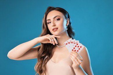 Poker game. Charming woman with playing cards on light blue background