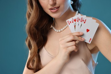 Poker game. Woman with playing cards on light blue background, closeup