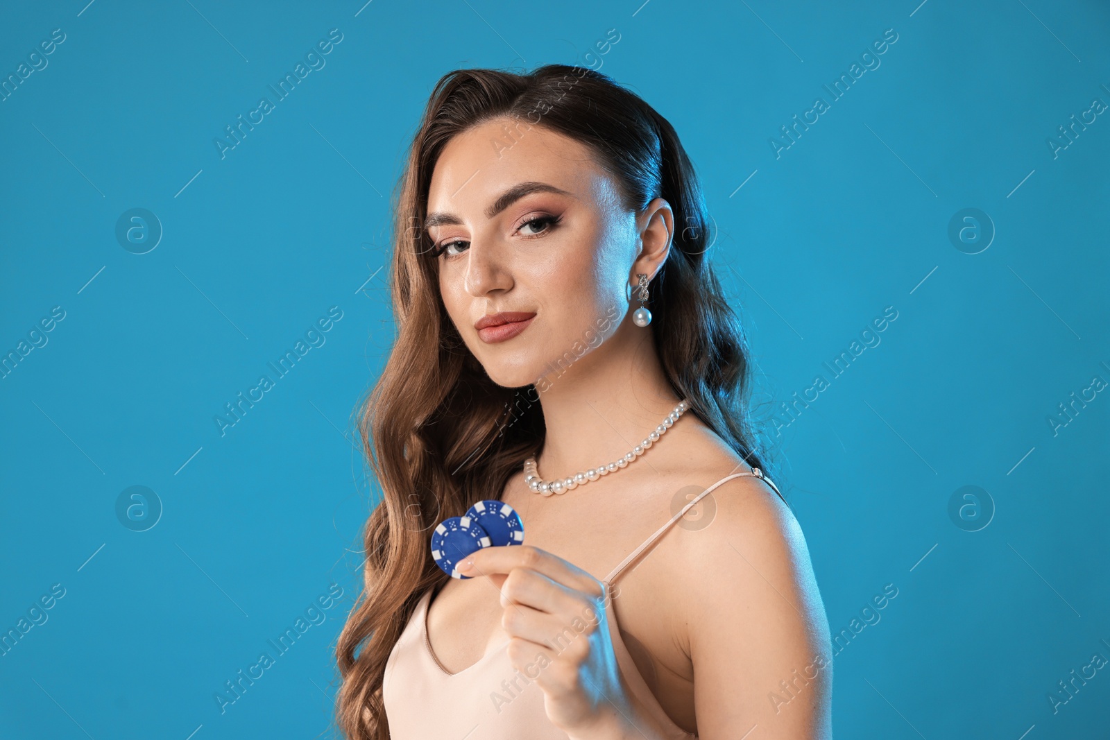 Photo of Charming woman with poker chips on light blue background