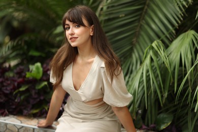 Photo of Beautiful woman posing near palm plants outdoors