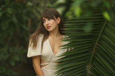 Portrait of beautiful woman with palm tree leaf outdoors