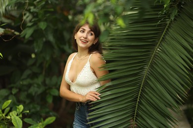 Portrait of smiling woman near palm leaves outdoors