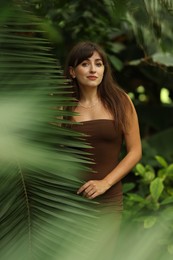 Portrait of beautiful woman near palm leaves outdoors