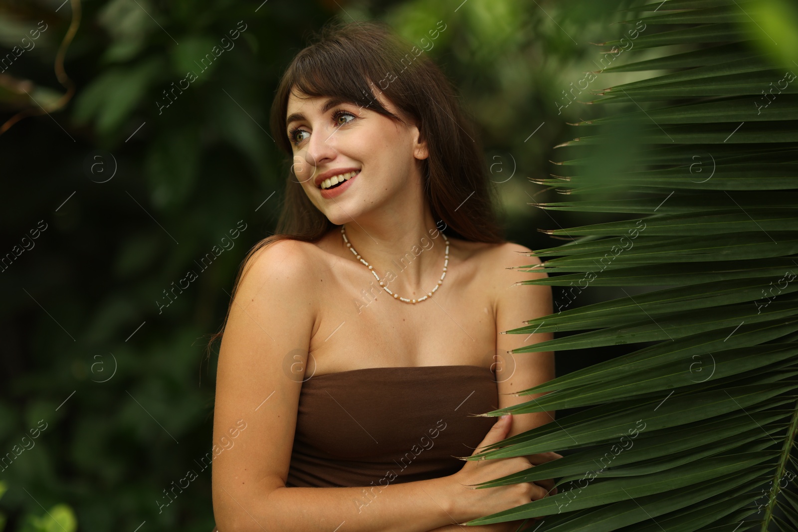 Photo of Portrait of smiling woman near palm leaves outdoors