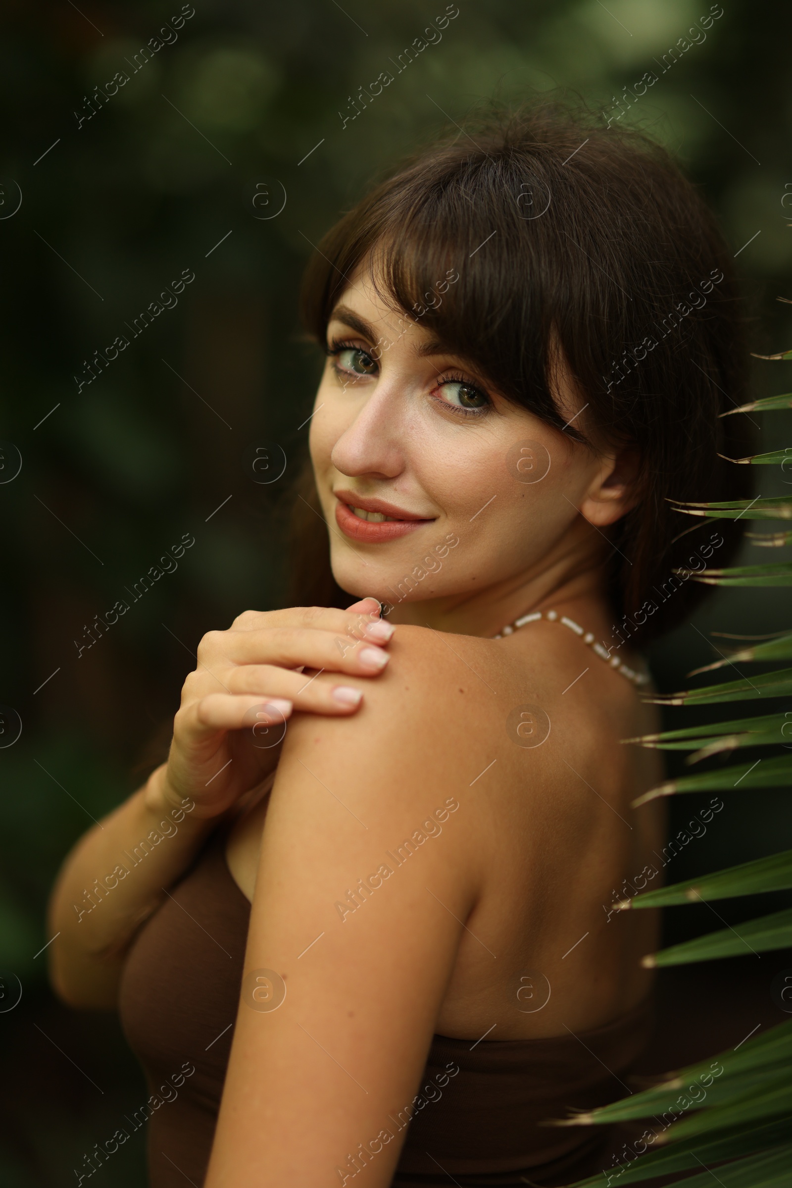 Photo of Portrait of smiling woman near palm leaves outdoors