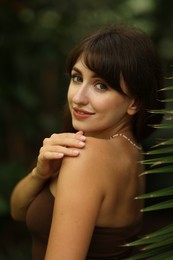 Portrait of smiling woman near palm leaves outdoors