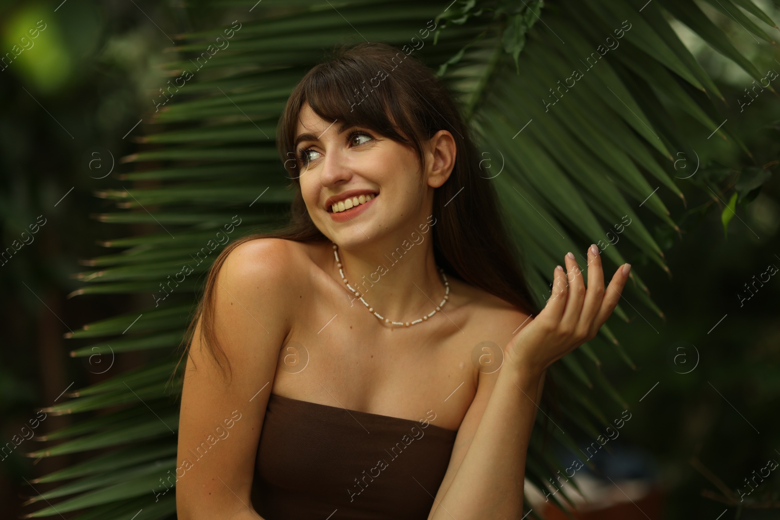 Photo of Portrait of smiling woman near palm leaves outdoors