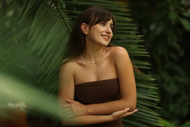 Portrait of smiling woman near palm leaves outdoors