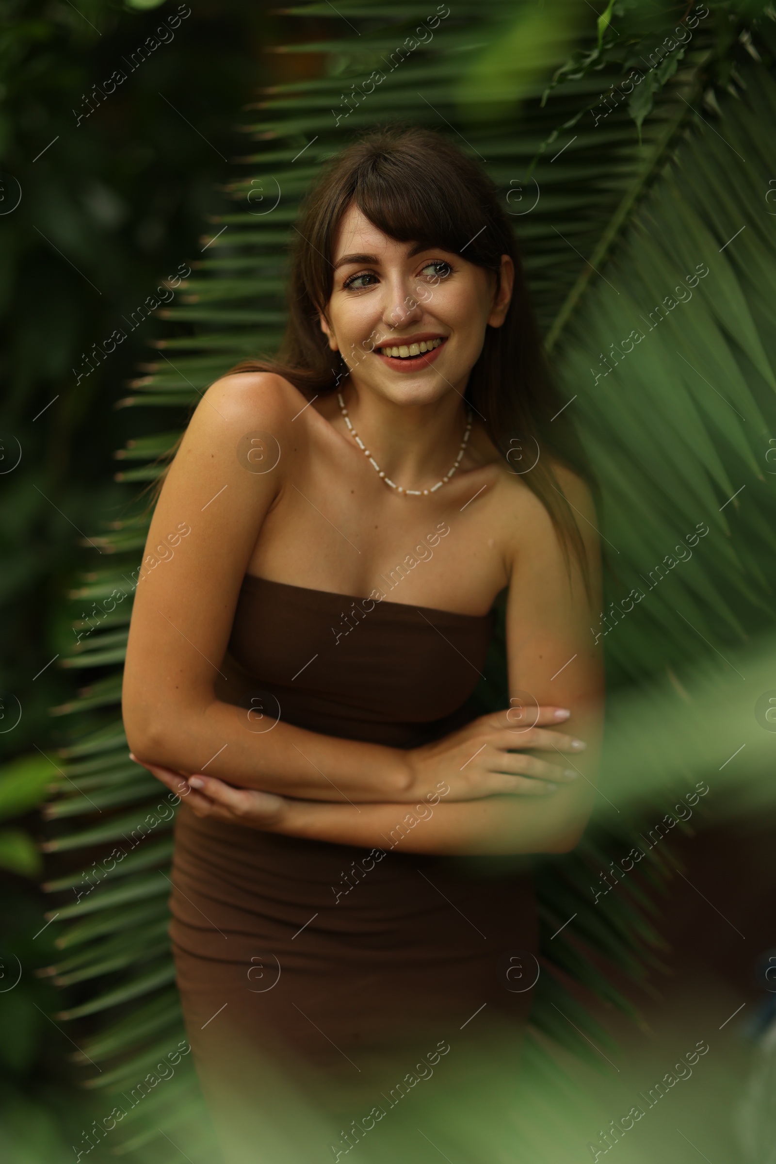 Photo of Portrait of smiling woman near palm leaves outdoors