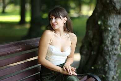 Smiling woman sitting on bench in park