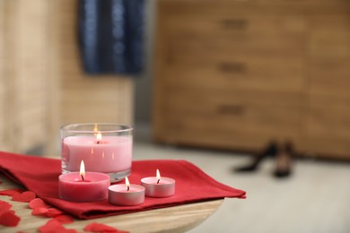 Burning candles, napkin and red paper hearts on wooden table indoors, space for text