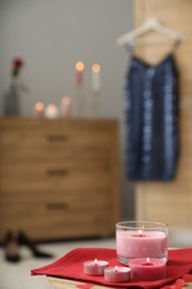 Burning candles, napkin and red paper hearts on wooden table indoors