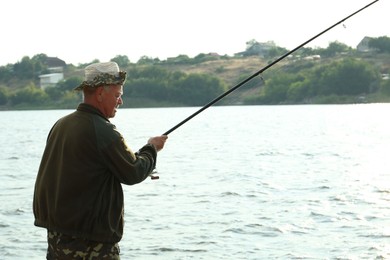 Photo of Fisherman with rod fishing near lake at summer