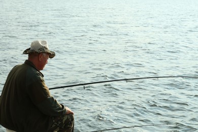 Fisherman with rod fishing near lake at summer. Space for text