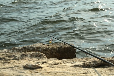 One fishing rod on shore near lake outdoors