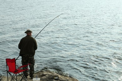 Fisherman with rod fishing near lake at summer, back view. Space for text