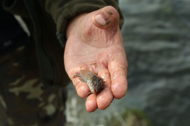 Fisherman holding small fish in hand, closeup