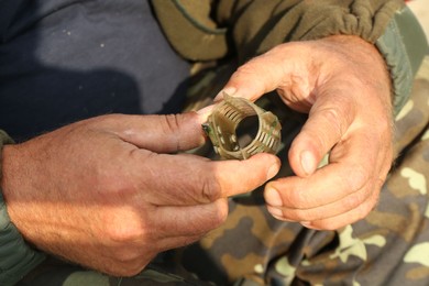 Senior fisherman holding fishing equipment outdoors, closeup