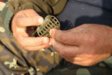 Senior fisherman holding fishing equipment outdoors, closeup