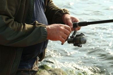 Fisherman with rod fishing near lake at summer, closeup