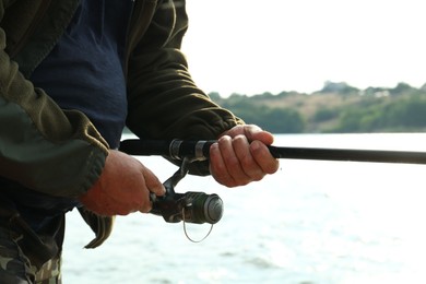 Fisherman with rod fishing near lake at summer, closeup