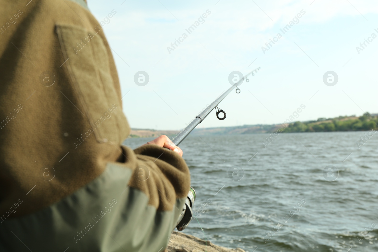 Photo of Fisherman with rod fishing near lake at summer, closeup