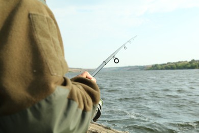 Fisherman with rod fishing near lake at summer, closeup