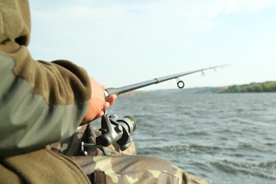 Fisherman with rod fishing near lake at summer, closeup