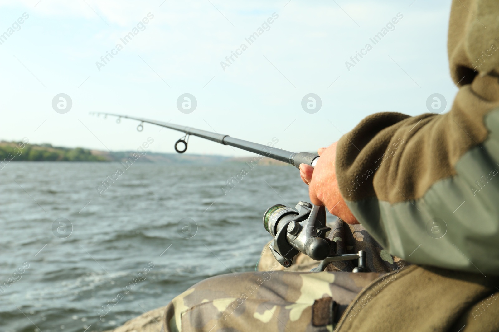 Photo of Fisherman with rod fishing near lake at summer, closeup