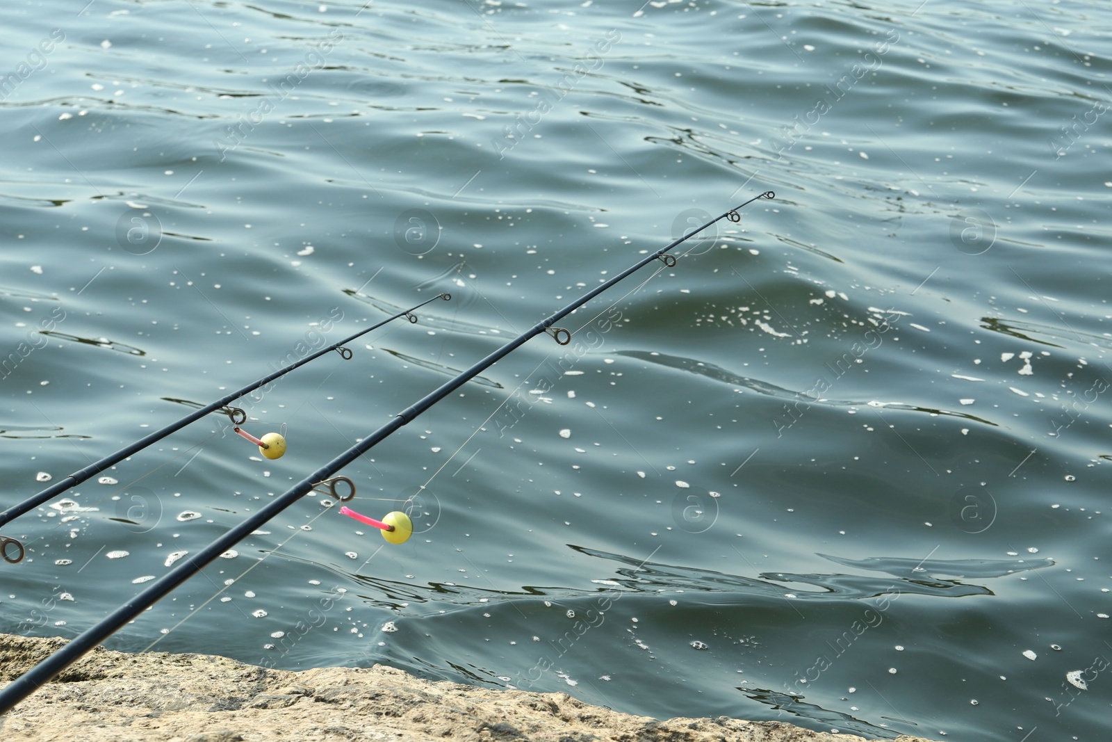 Photo of Two fishing rods on shore near lake outdoors