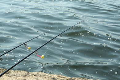 Two fishing rods on shore near lake outdoors