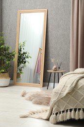 Photo of Large mirror near gray wall in bedroom. Interior design