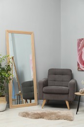 Photo of Large mirror near light gray wall in room. Interior design