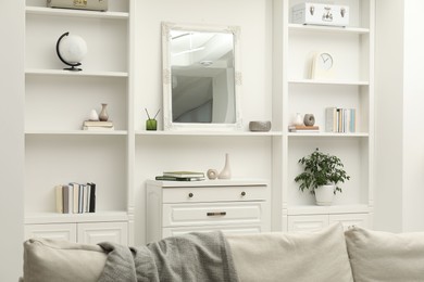 Photo of Mirror on white shelf in room. Interior design